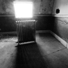 Radiator in abandoned apartment backlit by window